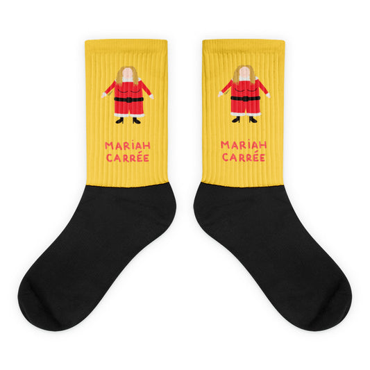 Paire de chaussettes jaunes et noires illustrant un personnage féminin carré en costume de Noël rouge, avec l'inscription "MARIAH CARRÉE" en lettres rouges.