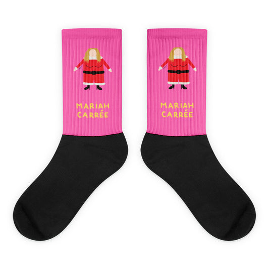 Paire de chaussettes roses et noires illustrant un personnage féminin carré en costume de Noël rouge, avec l'inscription "MARIAH CARRÉE" en lettres jaunes.