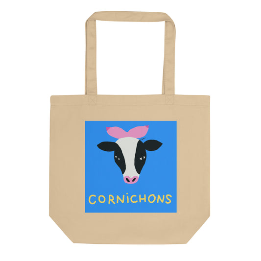 Tote bag beige en coton bio affichant un carré bleu avec une tête de vache dont les cornes sont des seins roses, titre Cornichons en jaune.